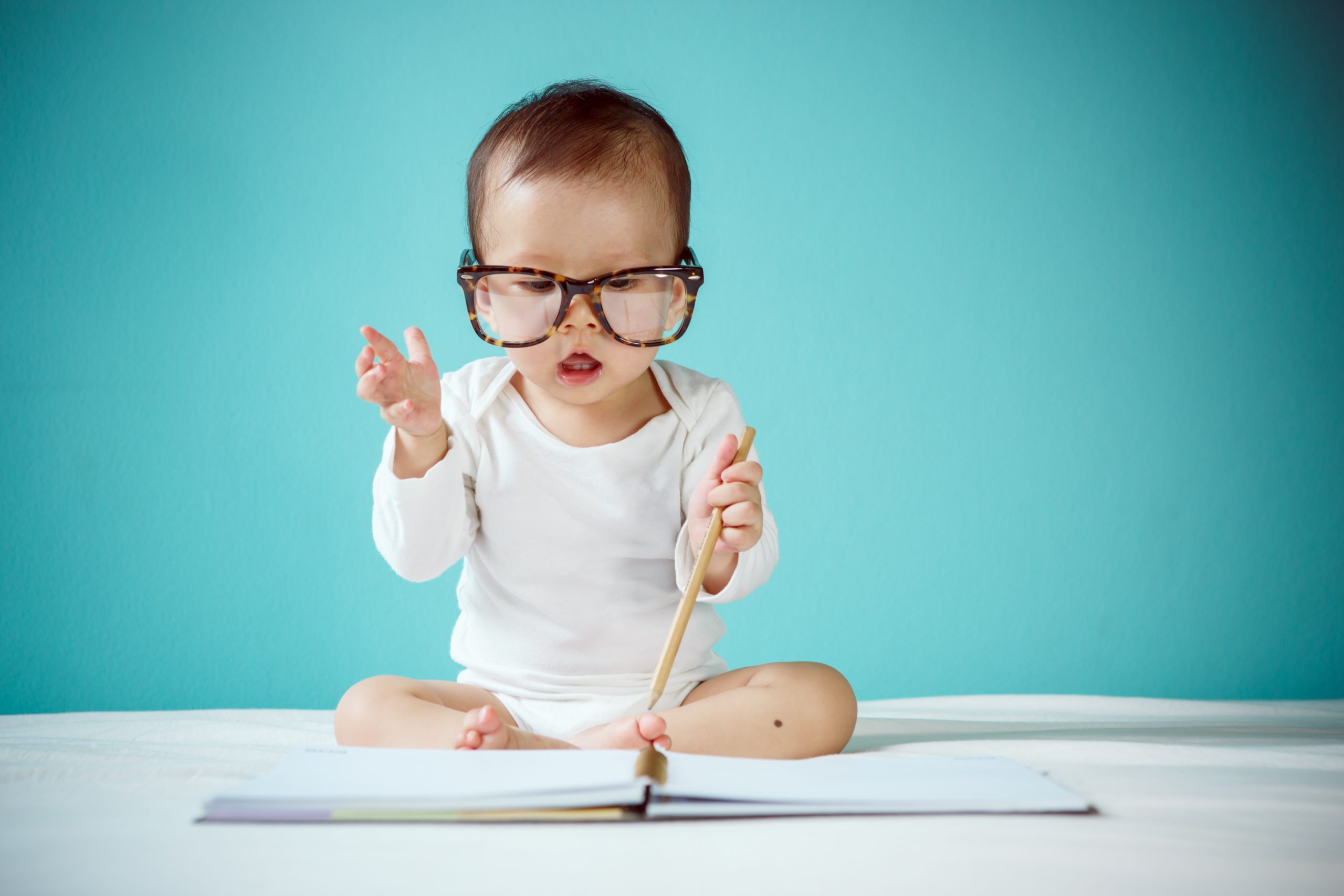 Cute Asian baby girl lying on stomach on bed, studio shot frequent questions image